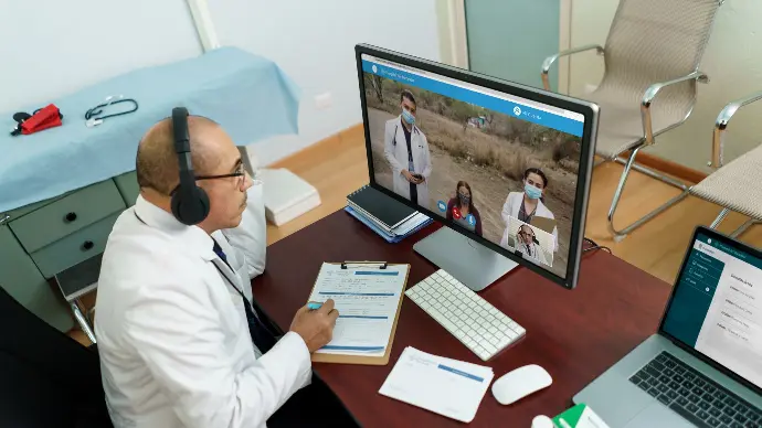A remote doctor with headset interacting with a remote patient and physicians.